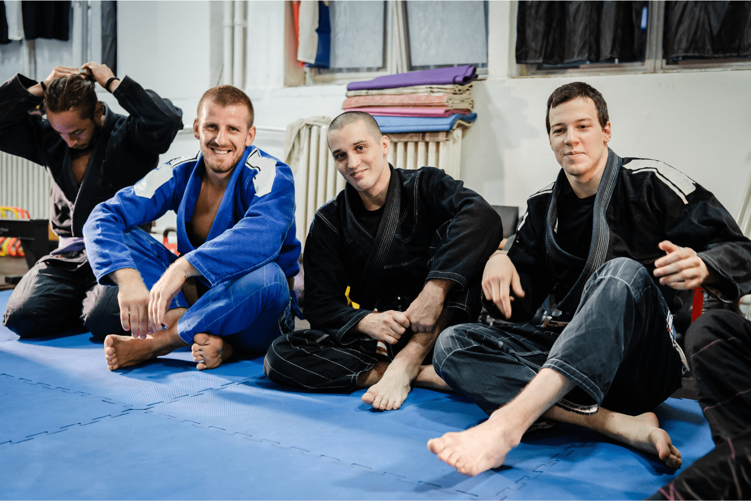 Luchadores de Brazilian Jiu-Jitsu sentados juntos en el tatami, compartiendo un momento de camaradería.